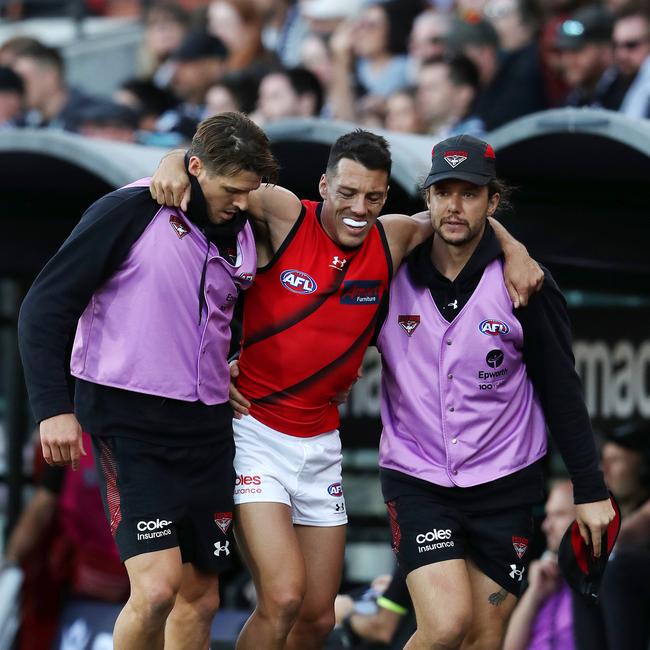 Bomber Dylan Shiel is helped off the field in the hands of trainer. Picture: Getty Images