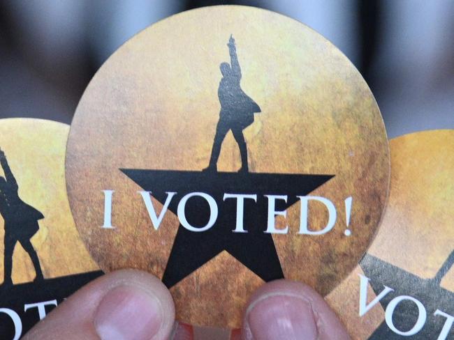 An election worker displays the "Hamilton"-themed "I Voted" stickers at the vote center for the US presidential election at the Pantages Theatre in Hollywood, California on October 30, 2020. - The theatre's second run of the hit Broadway musical "Hamilton" was cancelled due to the Covid-19 pandemic. (Photo by Robyn Beck / AFP)