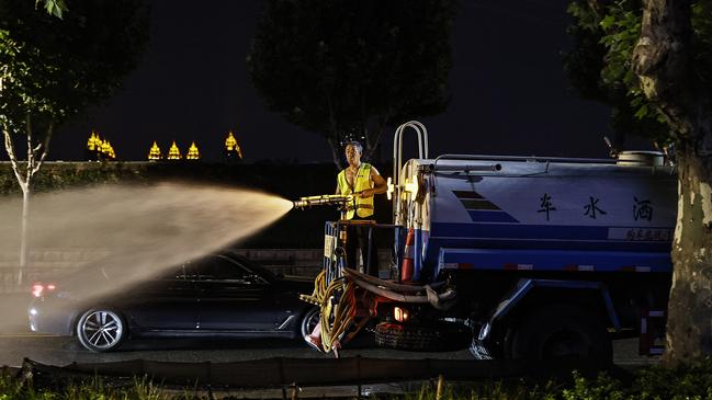 Workers water plants at night during a heatwave in Wuhan, China as meteorological departments issue high temperature red warnings across the nation. Picture: Getty Images