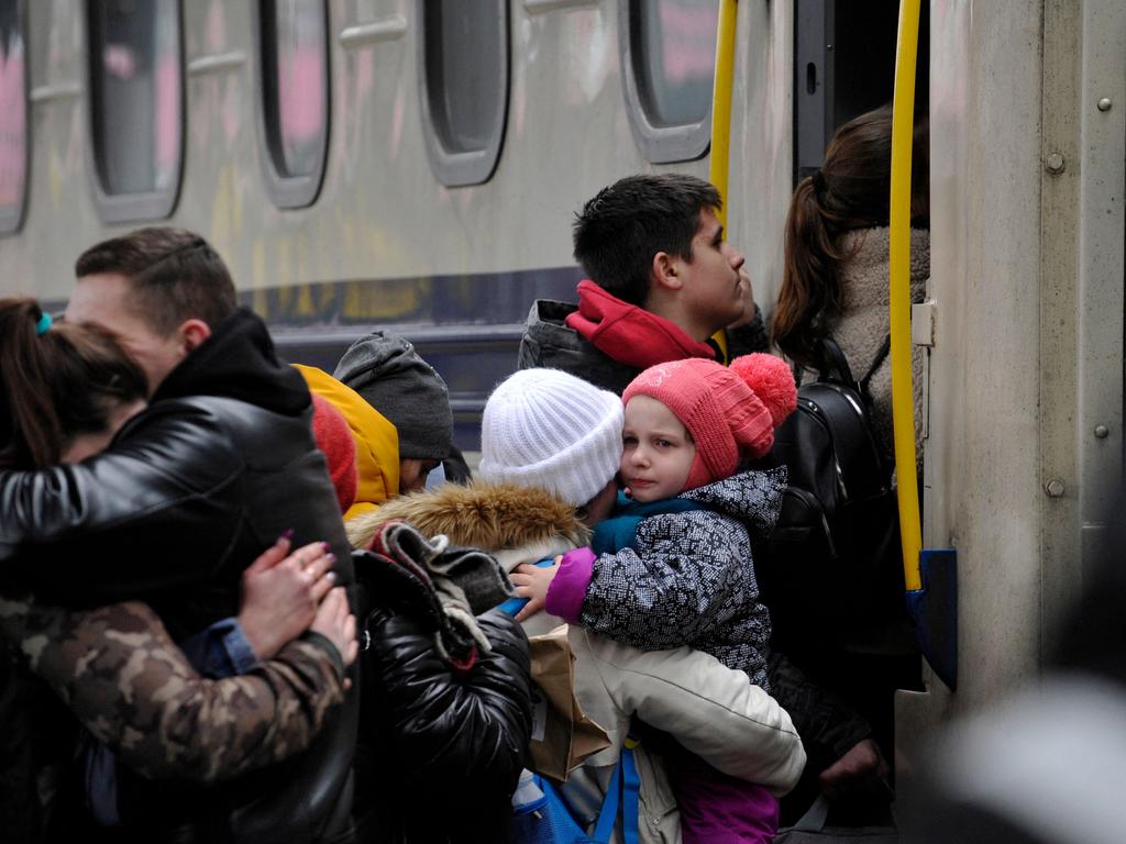 A woman holds a toddler before stepping up in an evacuation train as a man hugs a woman. Picture: AFP