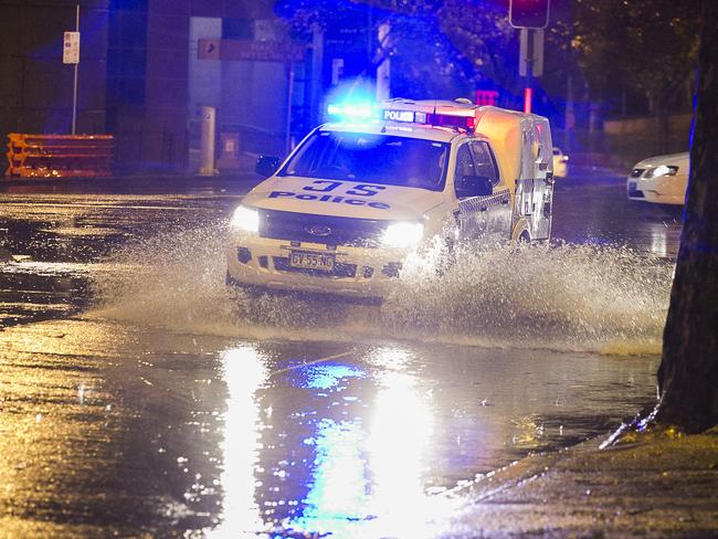 A police vehicle with lights flashing negotiates flooding at the intersection of Eddy and Pitt St in Sydney's CBD. Photo: Chris McKeen