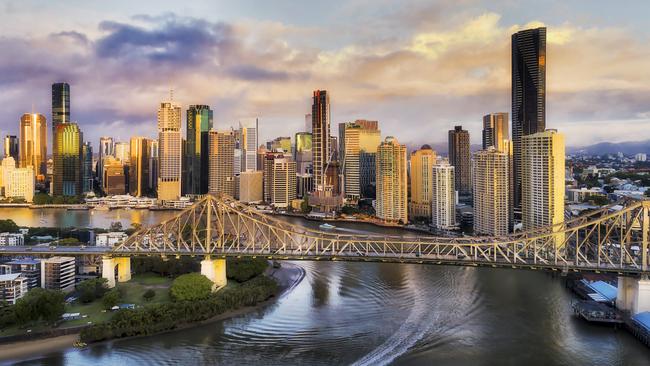 Developing Queensland – Close to Story Bridge across Brisbane River in front of Brisbane city CBD high-rise business and apartment towers with fast ferry on the water under the bridge.