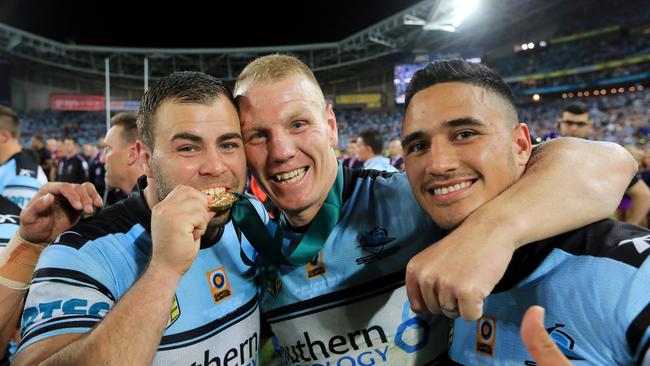 Wade Graham takes a bite of Luke Lewis's Clive Churchill Medal with Valentine Holmes. Picture: Mark Evans