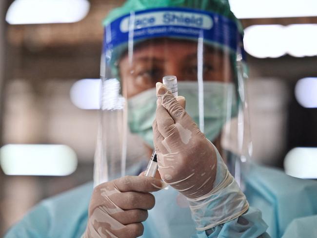 A health worker administers the CoronaVac vaccine, developed by China's Sinovac firm, at a makeshift clinic in Bang Khae Market, after hundreds of residents in the district tested positive for the Covid-19 coronavirus in Bangkok on March 17, 2021. (Photo by Lillian SUWANRUMPHA / AFP)