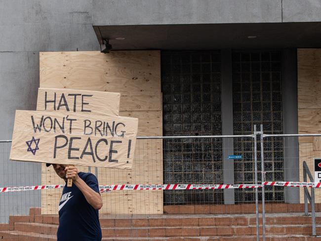 A man holds a placard saying “Hate won’t bring pease” in front of the Adass Israel synagogue. Picture: NewsWire