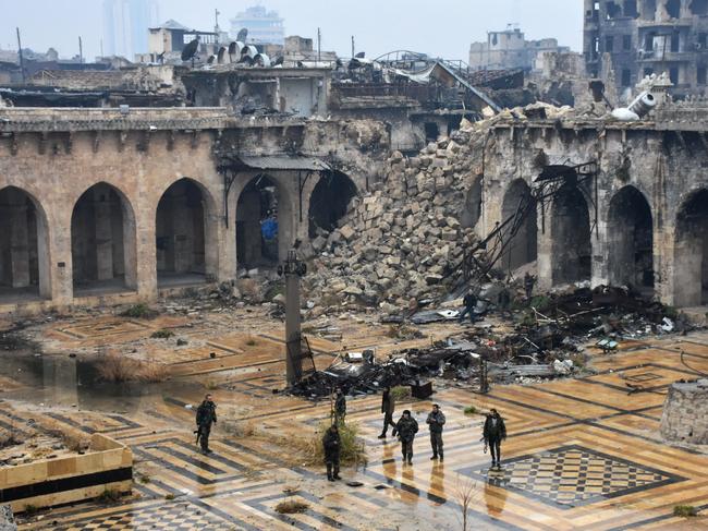 A general view shows Syrian pro-government forces walking in the ancient Umayyad mosque in the old city of Aleppo on December 13, 2016, after they captured the area. After weeks of heavy fighting, regime forces were poised to take full control of Aleppo, dealing the biggest blow to Syria's rebellion in more than five years of civil war. / AFP PHOTO / George OURFALIAN