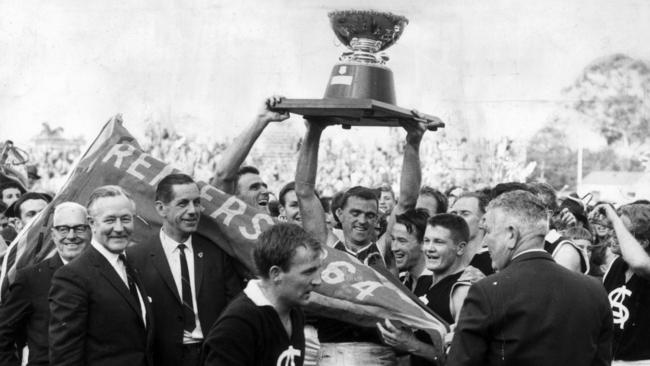 Footballer Neil Kerley holding the Thomas Seymour Hill Memorial trophy with teammate Ian Day after victory by South Adelaide in the 1964 SANFL grand final.