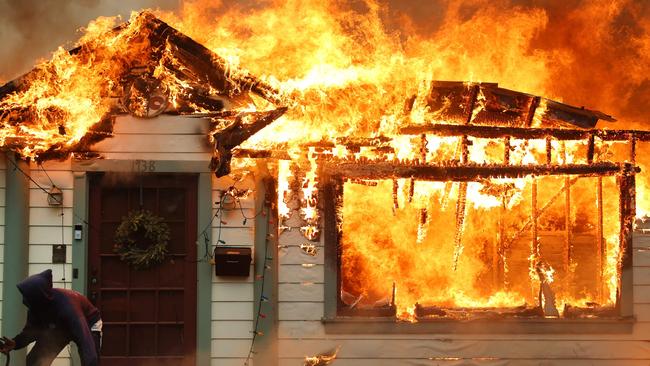 A resident turns on a garden hose in an effort to save a neighbouring home from catching fire during the Eaton Fire in Altadena, California. Picture: Getty Images