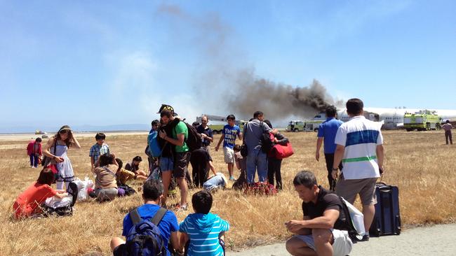 In this Saturday, July 6, 2013, photo provided by passenger Benjamin Levy, passengers from Asiana Airlines flight 214, many with their luggage, wait on the tarmac just moments after the plane crashed at the San Francisco International Airport in San Francisco. The flight crashed upon landing, and two of the 307 passengers aboard were killed. (AP Photo/Benjamin Levy)