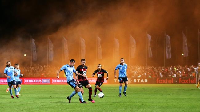 Action from Friday night’s Sydney derby as smoke from a flare drifts in the background. Picture: Getty Images