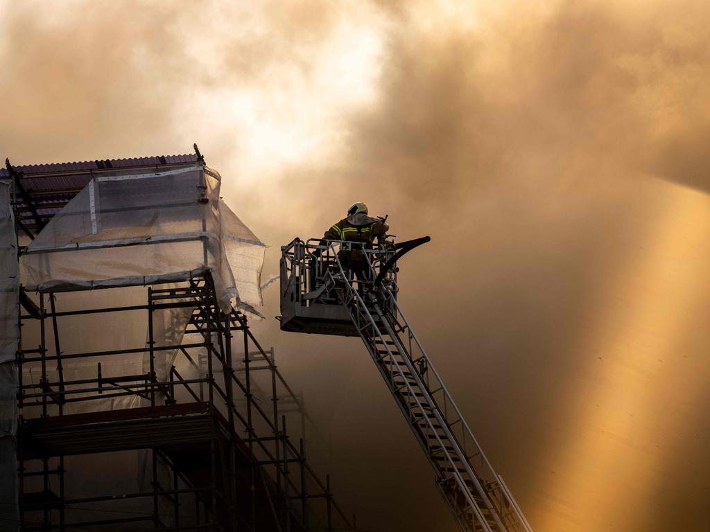 A fireman tries to extinguish the flames as smoke billows from the historic Boersen stock exchange building. Picture: Ritzau Scanpix / AFP