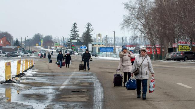 People carry their luggage as they walk to Russian side at the check point of Ukrainian-Russian border, 40 km from the Ukrainian city of Kharkiv. Picture: Sergey Bobok/AFP