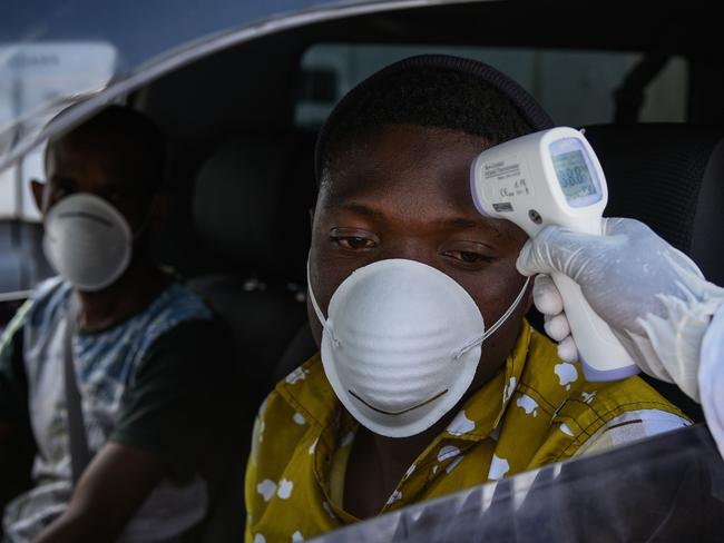 TOPSHOT - A staff member of the Ministry of Health measures the temperature of drivers and passengers during the testing of the COVID-19 Coronavirus on the highway in Nakuru, Kenya, on March 31, 2020. - Kenya has so far recorded 50 cases of coronavirus, and one death. (Photo by Suleiman MBATIAH / AFP)