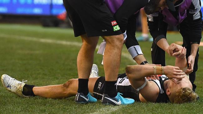 Adam Treloar is attended to by trainers after injuring his hamstrings.