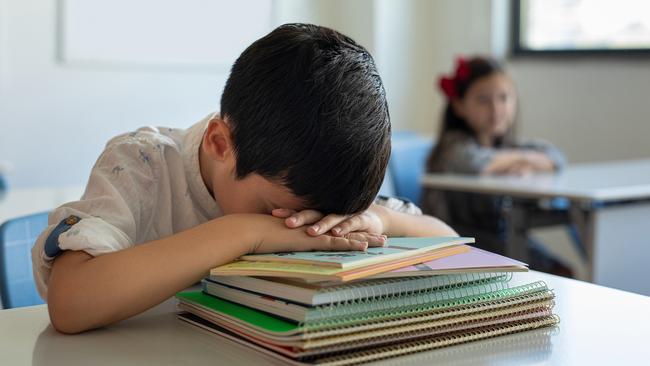 Young boy sleeping at her desk in a classroom