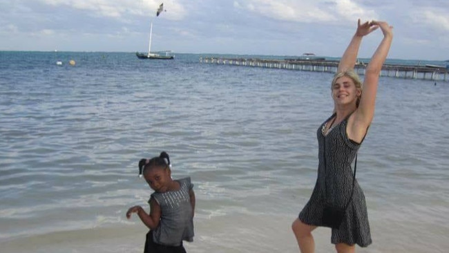 Elly Warren, who died mysteriously in Tofo, Mozambique in November 2016, pictured here dancing with an African child on a beach in South Africa in 2015. Picture: Supplied