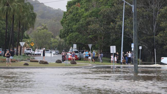Local residents from Lakewoods Elanora watch as drivers try to get through flood waters. Photo: Scott Powick
