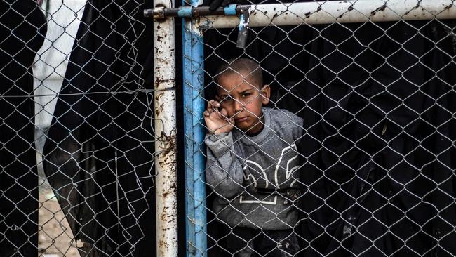 A child waits behind a wire fence in al-Hawl camp, which houses relatives of Islamic State (IS) group members in Syria. Picture: AFP