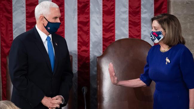 House Speaker Nancy Pelosi speaks with Vice President Mike Pence while wearing protective masks during a joint session of Congress to certify Joe Biden as the next US president in the US capitol in Washington.