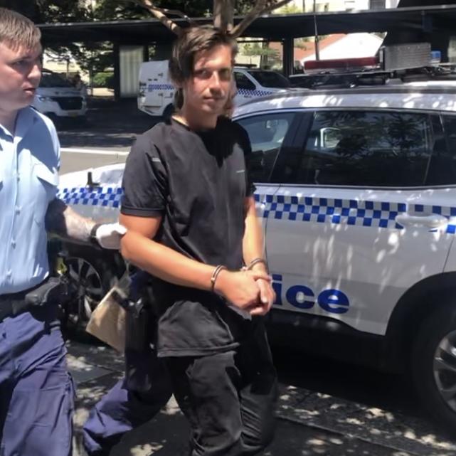 An officer leads Jack McLean into Manly Police Station after his arrest. Picture: Jim O’Rourke