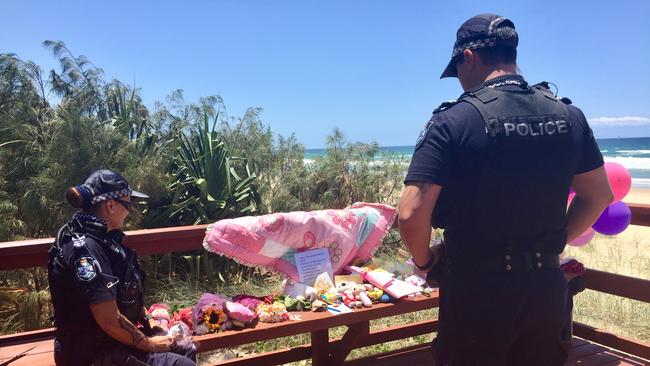 Queensland police officers wipe away tears as they bring toys and pay their respects near where the baby girl was found dead in the early hours of Monday morning