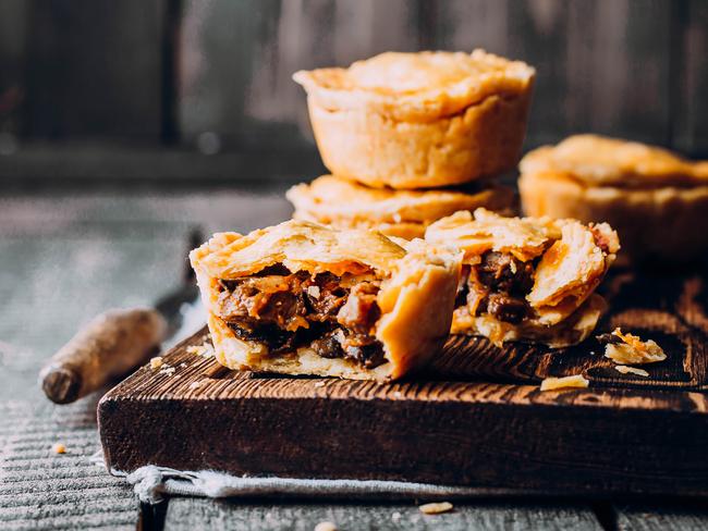 Fresh Traditional Australian meat mini pie on the wooden board on table background, closeup with copy space, rustic style