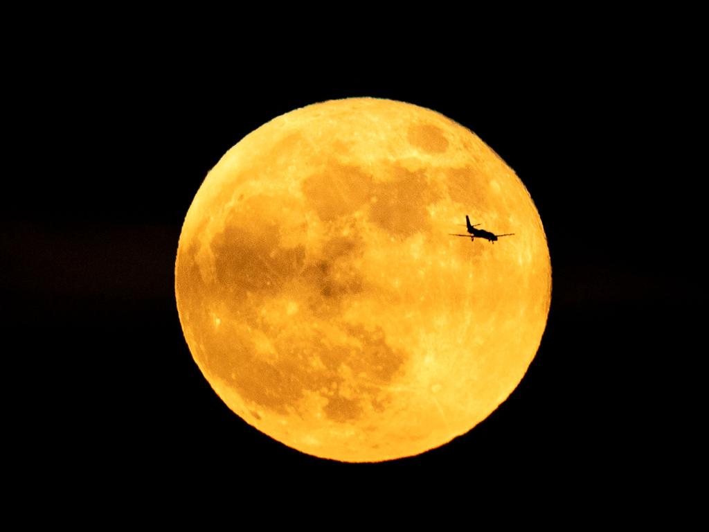 The silhouette of a plane is seen in front of the full moon in Rome. Picture: AFP