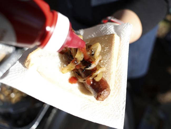 A volunteer hands out a ‘democracy sausage’. Picture: AFP