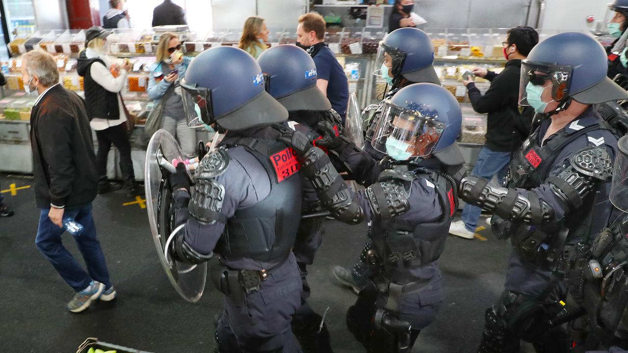 Police march past shoppers at the Queen Victoria Markets. Picture: David Crosling