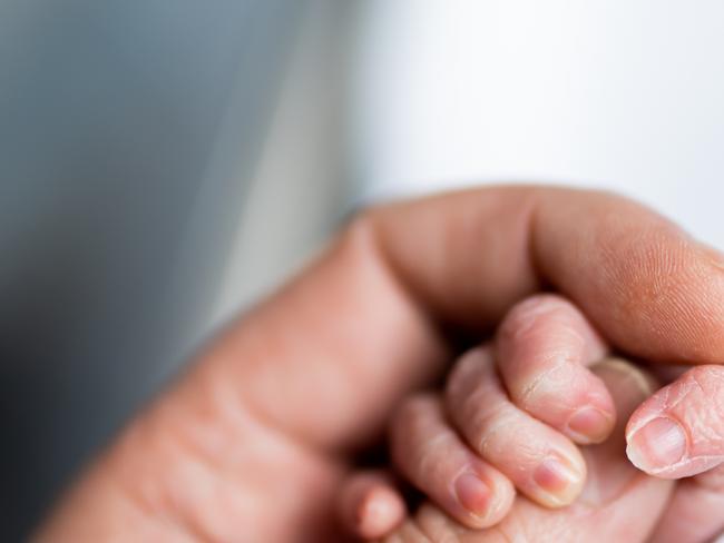 Hand of newborn baby who has just been born holding the finger of his father's hand.CREDIT ISTOCK