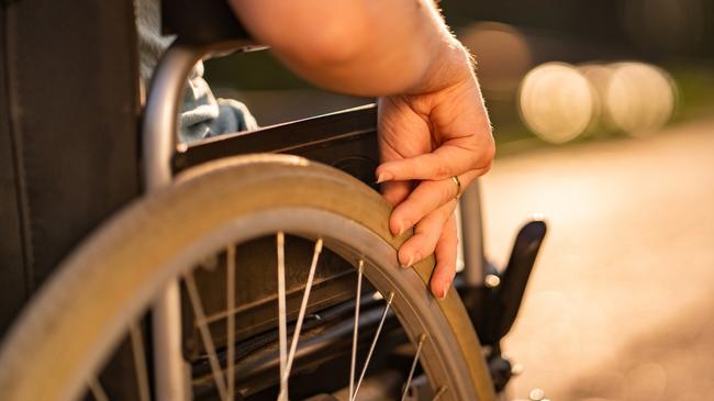 Close up women hand holding wheel on a wheelchair during sunset