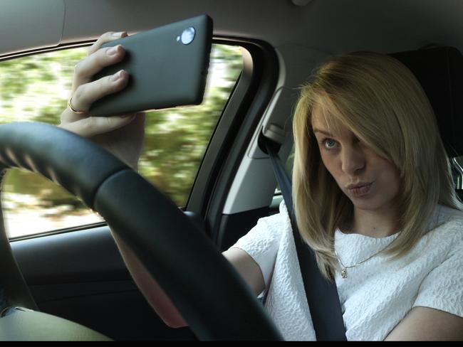 Woman taking a "selfie" while driving. Photo: Supplied (Ford UK, 2014). ‏‎ Posed by model