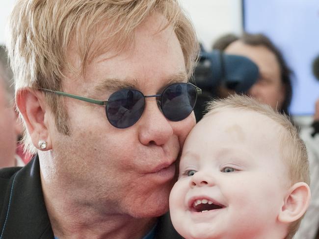 FILE - This is a Sept. 12, 2009 file photo of Pop singer Elton John as he kisses baby Lev during a news conference at a orphanage for HIV-positive children in the town of Makeyevka outside Donetsk, Ukraine. Elton John's partner David Furnish said Tuesday Dec. 8, 2009 that the musician was devastated that he wasn't allowed to adopt baby Lev a Ukrainian child, but plans to support the boy anyway. The 62-year-old pop star met 14-month-old Lev at a home for HIV-positive children in September. But he was refused permission to adopt the boy because he was too old and not married. (AP Photo/Ho, Fule)