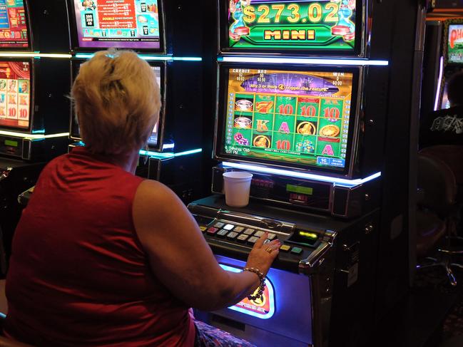 A woman tries her luck on a pokie machine.