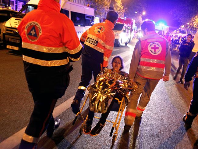 Terror in the streets ... a woman being evacuated after the shooting at the Bataclan theatre in Paris. Picture: AP