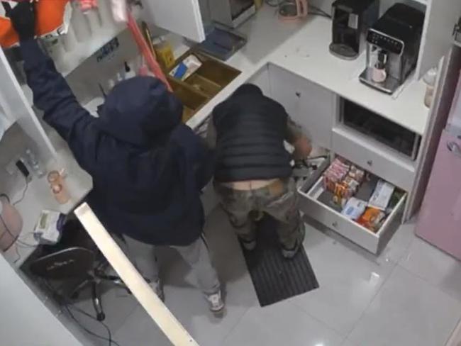 The oafish burglar flashes a plumber’s crack as he plunders a Sunbury store. Picture: 9News