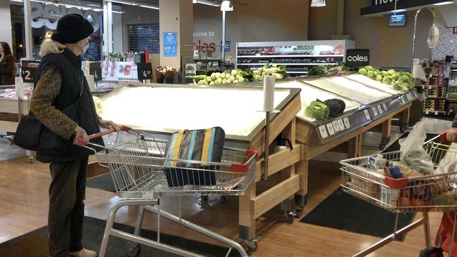 A shopper surveys empty shelves in the fruit and vegetable section of a Melbourne supermarket. There are fears supply chains could be interrupted nationwide. Picture: David Crosling