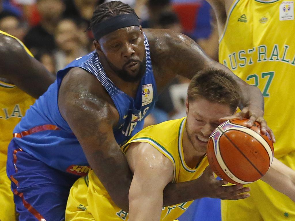 Australia's Mathew William Develladova is fouled by the Philippines' Andray Blache, center, during the FIBA World Cup Qualifiers Monday, July 2, 2018 at the Philippine Arena in suburban Bocaue township, Bulacan province north of Manila, Philippines. Australia defeated the Philippines 89-53 via default following a brawl in the third quarter. At left is Australia's Thon Marial Maker. (AP Photo/Bullit Marquez)