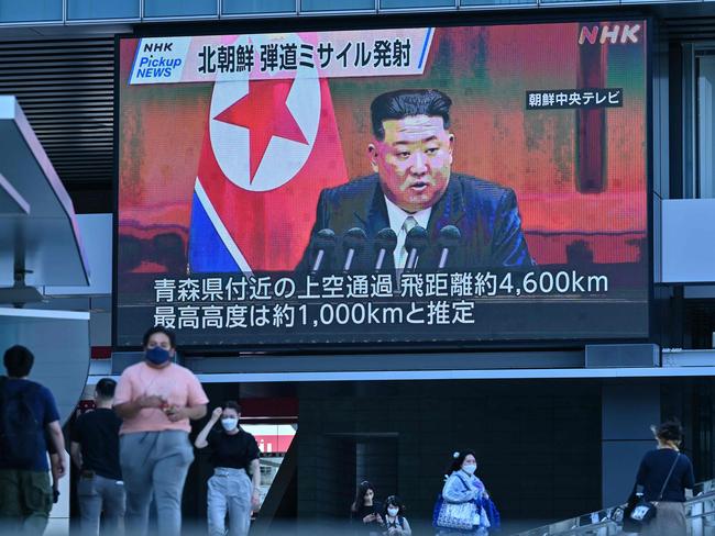 Japanese pedestrians walk under a large video screen showing images of North Korea's leader Kim Jong-un during a news update in Tokyo. Picture: AFP