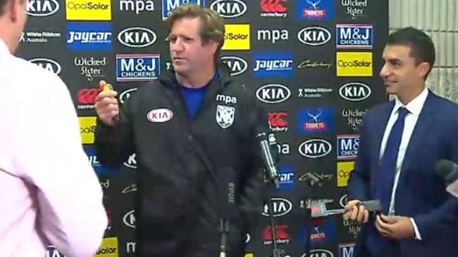 Des Hasler pulls out a stopwatch in his press conference.