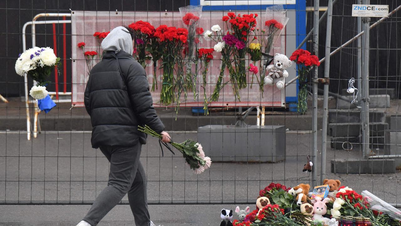 A woman lays flowers at a makeshift memorial on Saturday. Picture: AFP