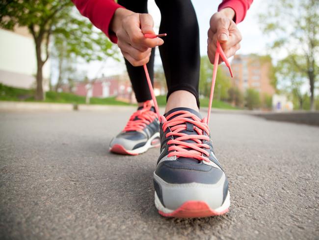 Sporty woman tying shoelace on running shoes before practice. Female athlete preparing for jogging outdoors. Runner getting ready for training. Sport active lifestyle concept. Close-upGeneric, istock