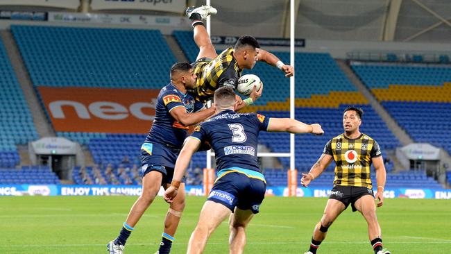 Warriors winger David Fusitu’a flies high to catch a ball against the Titans at Cbus Super Stadium but it was the home side that rose to the top. Picture: Getty Images