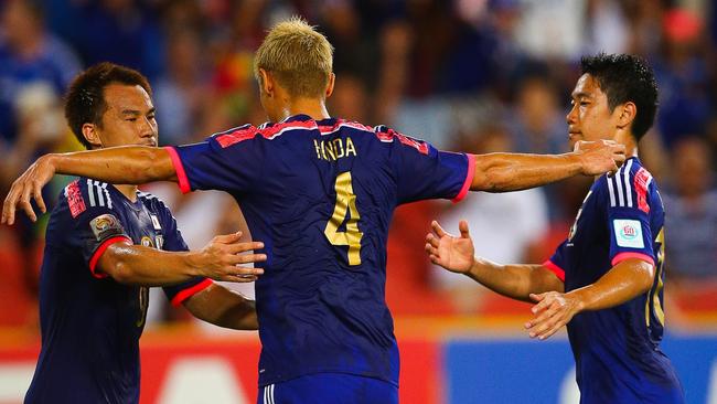 Keisuke Honda (C) celebrates his penalty goal with teammates Shinji Okazaki (L) and Shinji Kagawa (R) of Japan kicks a penalty kick during the first round Asian Cup football match between Japan and Iraq at the Suncorp Stadium in Brisbane on January 16, 2015. AFP PHOTO / PATRICK HAMILTON ---IMAGE RESTRICTED TO EDITORIAL USE - STRICTLY NO COMMERCIAL USE---