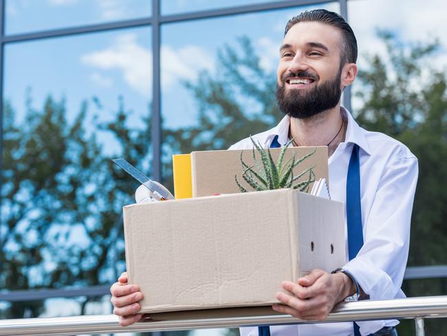 happy businessman with cardboard box with office supplies in hands standing outside office building, quitting job concept. quit job happy. ISTOCK