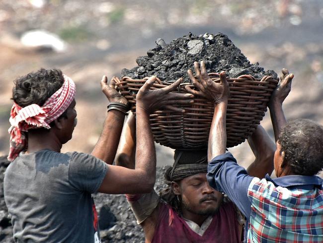 In this picture taken on October 14, 2021, workers prepare to load coal onto a truck at the Jharia coalfield in Dhanbad in India's Jharkhand state. - Asia-Pacific accounts for about three-quarters of global coal consumption -- even as the region struggles with the environmental and public health impacts of global warming, from deadly levels of air pollution in India to extreme heatwaves and wildfires in Australia. (Photo by Gautam Dey / AFP) / TO GO WITH Climate-UN-COP26-Asia-coal,FEATURE by Haeril Halim and Sam Reeves