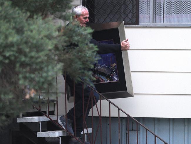 Logan councillor Russell Lutton removes a painting from a house in June.