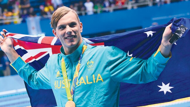 Australia's Kyle Chalmers waves his national flag during the medal ceremony.