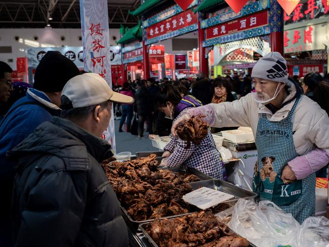 A vendor and customers at a market in Beijing. Picture: Nicolas Asfouri/AFP