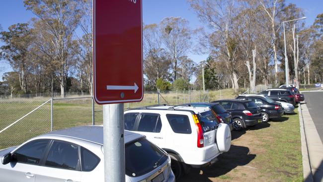 Cars parked on the grass verge at Edmondson Park railway station. 